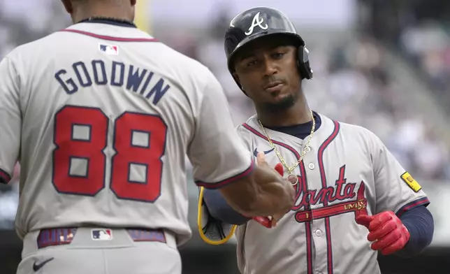 Atlanta Braves' Ozzie Albies, right, celebrates with first base coach Tom Goodwin (88) after hitting a single which led to Orlando Arcia scoring during the fifth inning of a baseball game against the New York Yankees, Sunday, June 23, 2024, in New York. (AP Photo/Pamela Smith)