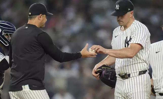 New York Yankees pitcher Carlos Rodón, right, hands the ball to manager Aaron Boone during the fourth inning of the team's baseball game against the Atlanta Braves, Friday, June 21, 2024, in New York. (AP Photo/Frank Franklin II)