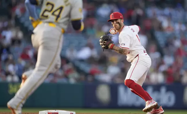 Los Angeles Angels shortstop Zach Neto, right, prepares to throw out Milwaukee Brewers' Christian Yelich at first to complete a double play after forcing out William Contreras, left, during the third inning of a baseball game Tuesday, June 18, 2024, in Anaheim, Calif. (AP Photo/Ryan Sun)