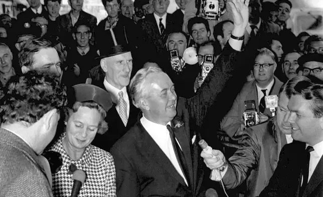 FILE - Britain's Labour Party leader Harold Wilson waves as he and his wife arrive at Euston Station, London, from his constituency in Liverpool, Oct. 16, 1964. Britain’s upcoming general election on July 4, 2024 is widely expected to lead to a change of government for the first time in 14 years. In 1964, the Conservative Party had been in power for 13 years and was on its fourth prime minister. The election was a race between the aristocratic Douglas-Home and Labour leader Harold Wilson, a young politician who was buzzing with ideas such as the need to harness the “white heat of technology” to modernize the ailing British economy. (AP Photo/File)