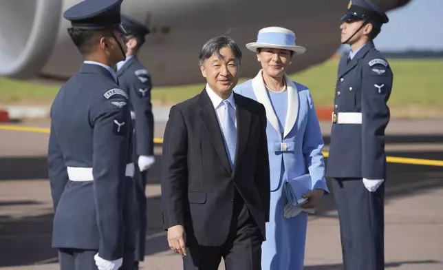 Emperor Naruhito and Empress Masako smile at the media walk through a guard of honour after arriving at Stansted Airport, England, Saturday, June 22, 2024, ahead of a state visit. The state visit begins Tuesday, when King Charles III and Queen Camilla will formally welcome the Emperor and Empress before taking a ceremonial carriage ride to Buckingham Palace. (AP Photo/Kin Cheung)
