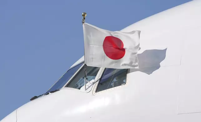 The Japanese flag flies form the cockpit window of the plane carring Emperor Naruhito and Empress Masako as it arrives at Stansted Airport, England, Saturday, June 22, 2024, ahead of a state visit. The state visit begins Tuesday, when King Charles III and Queen Camilla will formally welcome the Emperor and Empress before taking a ceremonial carriage ride to Buckingham Palace. (AP Photo/Kin Cheung)