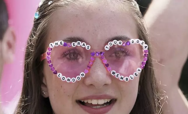A fan wearing sunglasses waits outside Wembley Stadium ahead of Taylor Swift's first London concert, during her Eras Tour, in London, Friday June 21, 2024. (Lucy North/PA via AP)