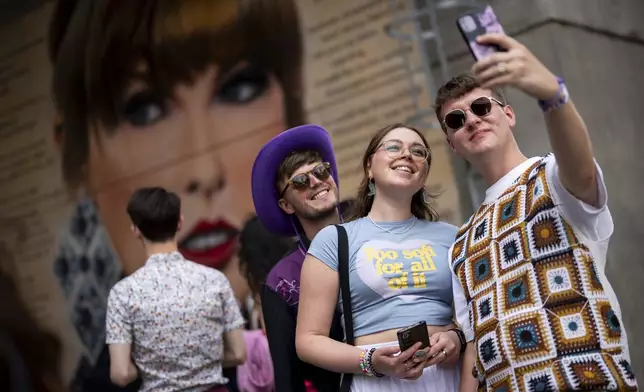 Taylor Swift fans pose for a photograph besides a mural, commissioned by London Mayor Sadiq Khan, before the first London concert of the Eras Tour on Friday, June 21, 2024 in London. (Photo by Scott A Garfitt/Invision/AP)