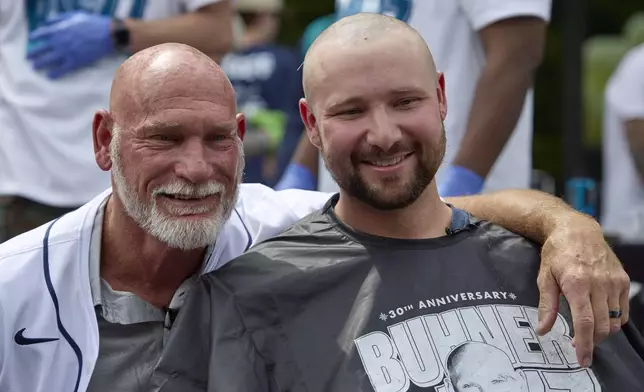 Seattle Mariners catcher Cal Raleigh, right, poses with former Mariners player Jay Buhner on Buhner Buzz Night, Thursday, June 13, 2024, in Seattle. The promotion is based on Buhner's shaved-head style. (AP Photo/John Froschauer)