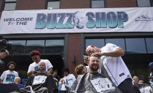 Seattle Mariners catcher Cal Raleigh has his head shaved by former Mariners player Jay Buhner on Buhner Buzz Night, Thursday, June 13, 2024, in Seattle. The promotion is based on Buhner's shaved-head style. (AP Photo/John Froschauer)