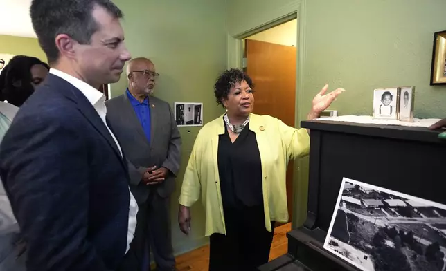 U.S. Transportation Secretary Pete Buttigieg, left, U.S. Rep. Bennie Thompson, D-Miss., center, listen as Reena Evers-Everette, points out photographs of her five-year-old self and her older brother Darrell Kenyatta Evers, then six, on top of her mother's piano, as a group of dignitaries toured the home of assassinated civil rights leader Medgar Evers, Friday, June 21, 2024, in Jackson, Miss. The house, the Medgar and Myrlie Evers National Monument, was one of the stops Buttigieg made as he spent Thursday and Friday in Mississippi, promoting projects that will be helped or will be receiving money from a federal infrastructure act. (AP Photo/Rogelio V. Solis, Pool)