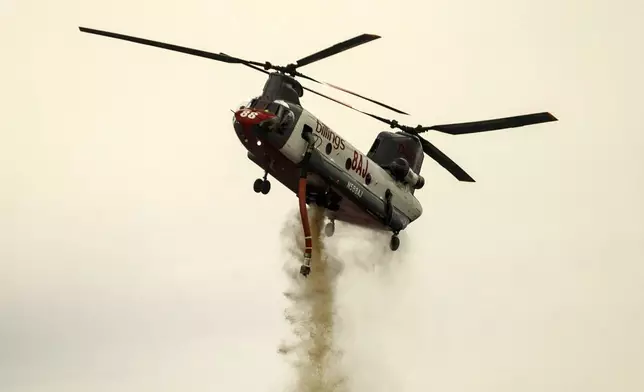 A helicopter drops water on the Apache Fire as it burns in Palermo, Calif., on Tuesday, Jun. 25, 2024. According to Cal Fire, more than a dozen new fires sparked by lightning. (AP Photo/Ethan Swope)