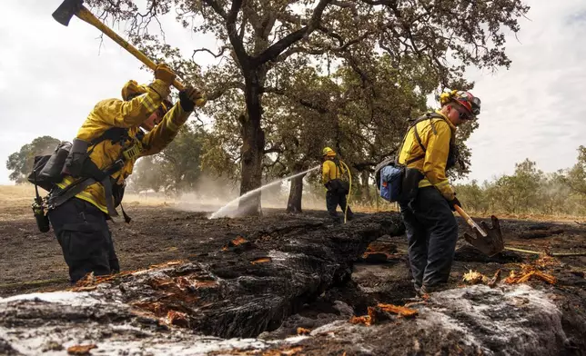 Firefighters mop up as the Apache Fire burns in Palermo, Calif., on Tuesday, Jun. 25, 2024. According to Cal Fire, more than a dozen new fires sparked by lightning. (AP Photo/Ethan Swope)