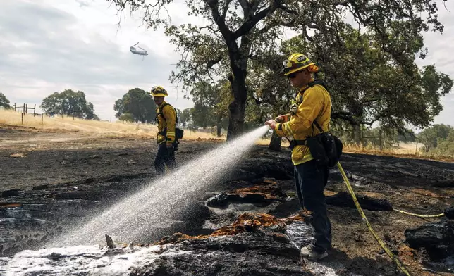 Firefighters mop up as the Apache Fire burns in Palermo, Calif., on Tuesday, Jun. 25, 2024. According to Cal Fire, more than a dozen new fires sparked by lightning. (AP Photo/Ethan Swope)