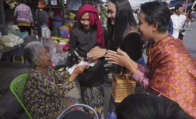 Ceremony performers receive money from an elderly during the He Neak Ta rituals in Phum Boeung village, northwest of Phnom Penh, Cambodia, Tuesday, June 11, 2024. Cambodian villagers on Tuesday took part in a rare traditional guardian spirit ceremony praying for good fortune, rain and prosperity, as they aimed to preserve this ancient tradition. (AP Photo/Heng Sinith)