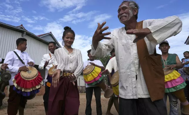 An elderly man joins dancers participating in the He Neak Ta rituals in Phum Boeung village, northwest of Phnom Penh, Cambodia, Tuesday, June 11, 2024. Cambodian villagers on Tuesday took part in a rare traditional guardian spirit ceremony praying for good fortune, rain and prosperity, as they aimed to preserve this ancient tradition. (AP Photo/Heng Sinith)