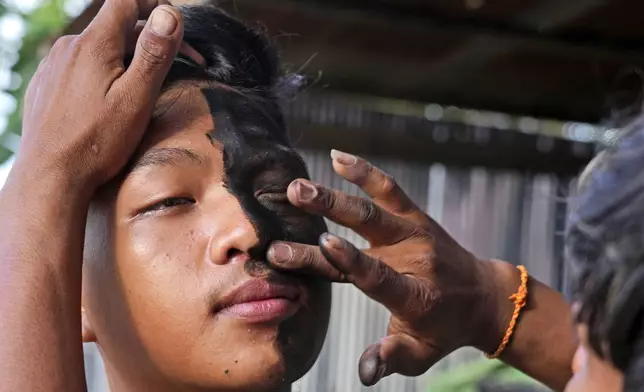 A boy has his face painted in the likeness of a spirit before participating in the He Neak Ta rituals in Phum Boeung village, northwest of Phnom Penh, Cambodia, Tuesday, June 11, 2024. (AP Photo/Heng Sinith)