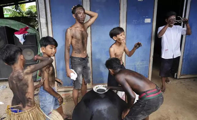 Young boys paint their bodies before participating in the He Neak Ta rituals in Phum Boeung village, northwest of Phnom Penh, Cambodia, Tuesday, June 11, 2024. Cambodian villagers on Tuesday took part in a rare traditional guardian spirit ceremony praying for good fortune, rain and prosperity, as they aimed to preserve this ancient tradition. (AP Photo/Heng Sinith)