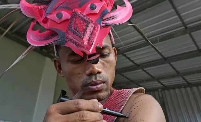 A man paints his body before participating in the He Neak Ta rituals in Phum Boeung village, northwest of Phnom Penh, Cambodia, Tuesday, June 11, 2024. Hundreds of Cambodian villagers on Tuesday took part in a rare traditional guardian spirit ceremony praying for good fortune, rain and prosperity, as they aimed to preserve this ancient tradition. (AP Photo/Heng Sinith)