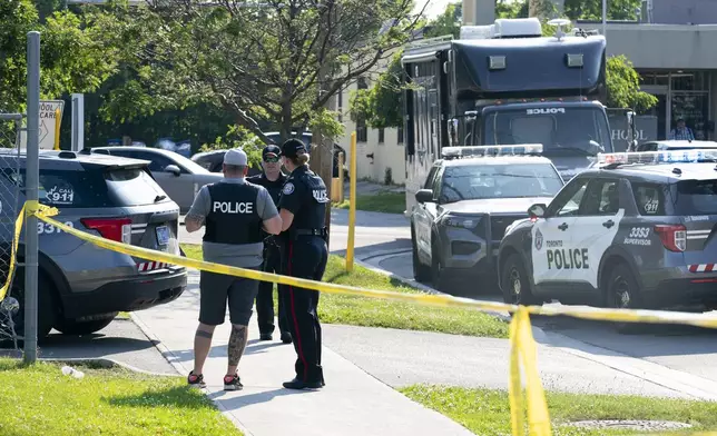 Toronto police officers investigate after several adults died in the lobby of an office space in Toronto, Monday, June 17, 2024. Police responded to reports of gunshots in an area near a school and a daycare. (Arlyn McAdorey/The Canadian Press via AP)