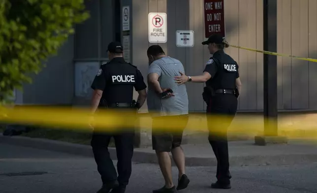 Toronto police officers comfort a man at the scene of a fatal shooting in Toronto, Monday, June 17, 2024. (Arlyn McAdorey/The Canadian Press via AP)