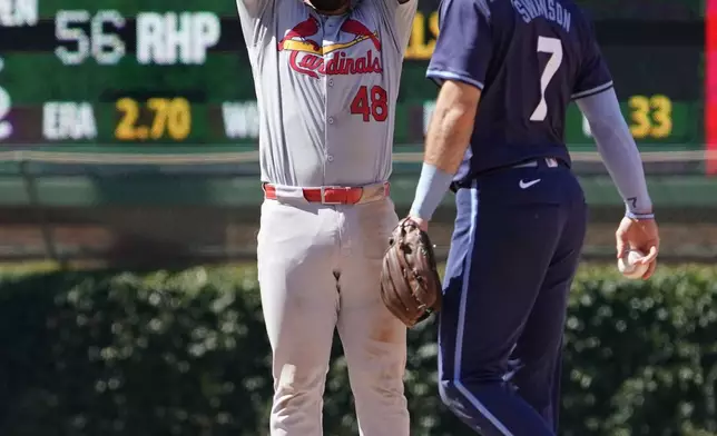 St. Louis Cardinals' Iván Herrera (48) gestures after hitting a one-run double as Chicago Cubs shortstop Dansby Swanson (7) stands nearby during the ninth inning of a baseball game Friday, June 14, 2024, in Chicago. (AP Photo/David Banks)