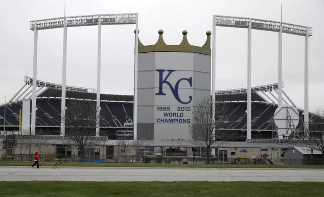 FILE - A woman and her dog walk past Kauffman Stadium, home of the Kansas City Royals baseball team, March 24, 2020, in Kansas City, Mo. The Kansas Legislature's top leaders endorsed helping the Kansas City Chiefs and the Kansas City Royals finance new stadiums in Kansas ahead of a special session set to convene Tuesday, June 18. The plan would authorize state bonds for stadium construction and pay them off with revenues from sports betting, the Kansas Lottery and new tax dollars generated in and around the new venues. (AP Photo/Charlie Riedel, File)