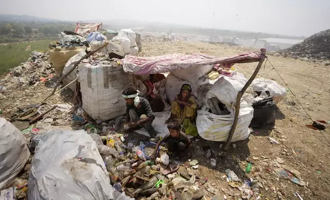 Waste pickers Arjun, 6, sorts recyclable items with his parents at a garbage dump site during a heat wave on the outskirts of Jammu, India, Thursday, June 19, 2024. As many as 4 million people in India scratch out a living searching through landfills for anything they can sell. (AP Photo/Channi Anand)