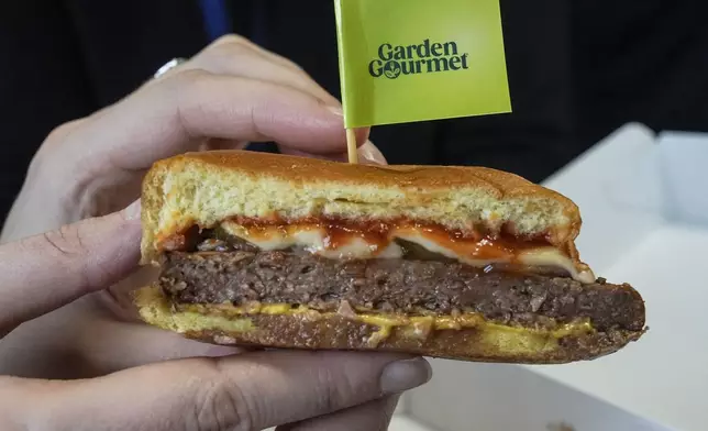 FILE - A member of the media displays a veggie cheese burger during a presentation of a veggie food line for spectators and athletes at the headquarters of the 2024 Paris Olympics in Paris on Dec. 12, 2023. (AP Photo/Michel Euler, File)