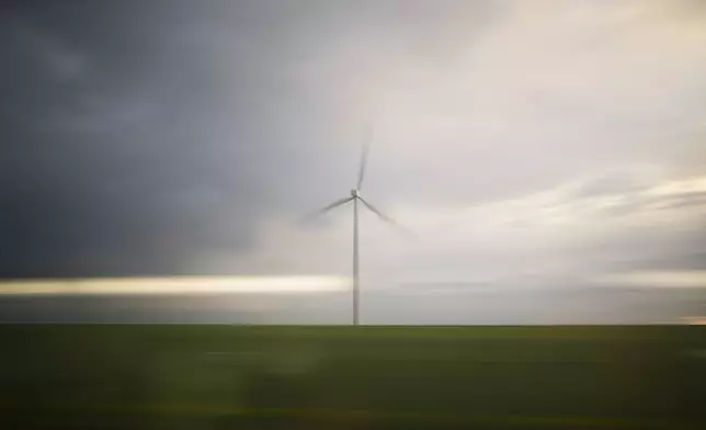 A wind turbine operates as seen a high-speed train from Paris to Marseille, France, Monday, May 27, 2024. (AP Photo/Daniel Cole)