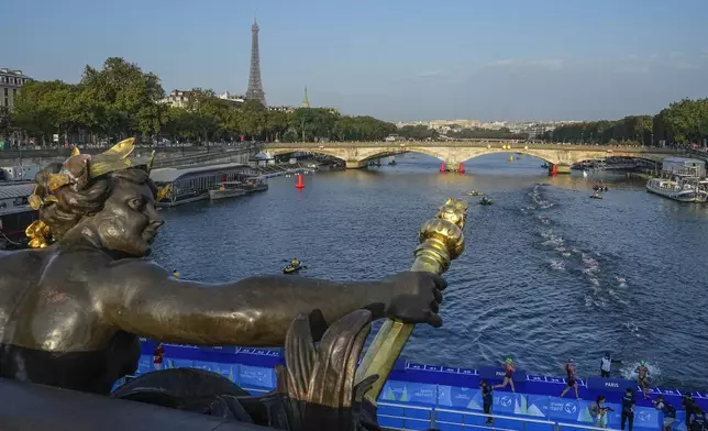 FILE - Athletes dive and swim in the Seine River from the Alexander III bridge on the first leg of the women's triathlon test event for the Olympic Games in Paris, Aug. 17, 2023. In 2024. (AP Photo/Michel Euler, File)