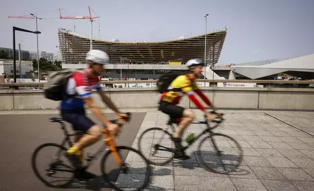 FILE - Cyclists ride near the Aquatic Center in Saint-Denis, north of Paris, July 10, 2023, in Paris. The venue will host artistic swimming, diving and water polo during the Olympics. (AP Photo/Thomas Padilla, File)