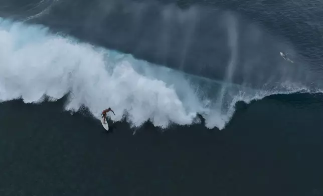 A surfer rides a wave in Teahupo'o, Tahiti, French Polynesia, Saturday, Jan. 13, 2024. (AP Photo/Daniel Cole)