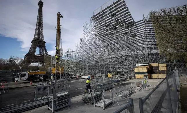 FILE - Workers build the stands for the upcoming Olympic Games on the Champ-de-Mars just beside the Eiffel Tower, in Paris, April 1, 2024 in Paris. (AP Photo/Thomas Padilla, File)