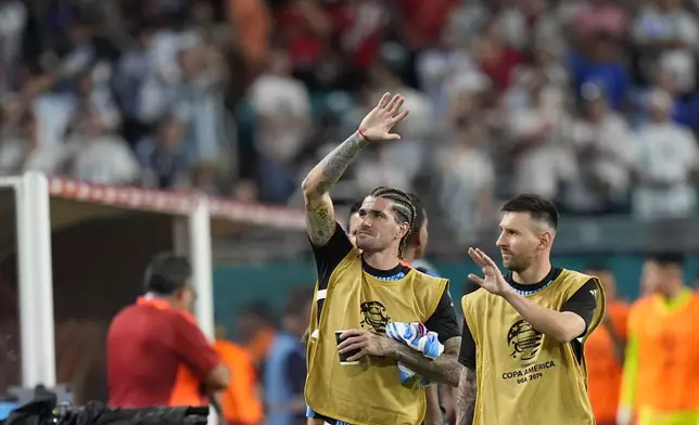 Argentina's Lionel Messi, right, and Rodrigo De Paul wave to fans during a Copa America Group A soccer match against Peru in Miami Gardens, Fla., Saturday, June 29, 2024. (AP Photo/Lynne Sladky)