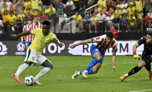 Brazil's Vinicius Junior, left, scores his side's opening goal against Paraguay during a Copa America Group D soccer match in Las Vegas, Friday, June 28, 2024. (AP Photo/David Becker)