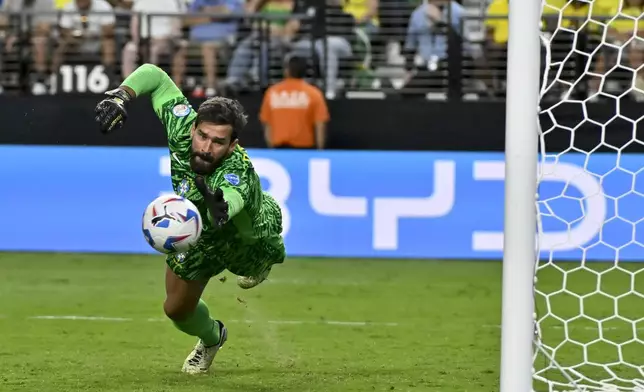 Brazil's goalkeeper Alisson stretches out for a save attempt during a Copa America Group D soccer match against Paraguay in Las Vegas, Friday, June 28, 2024. (AP Photo/David Becker)