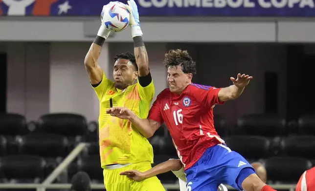 Peru's goalkeeper Pedro Gallese catches a ball beside Chile's Igor Lichnovsky during a Copa America Group A soccer match in Arlington, Texas, Friday, June 21, 2024. (AP Photo/Julio Cortez)