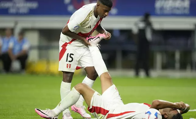 Peru's Carlos Zambrano lies on the field as teammate Miguel Araujo holds his leg during a Copa America Group A soccer match against Chile against Chile in Arlington, Texas, Friday, June 21, 2024. (AP Photo/Tony Gutierrez)