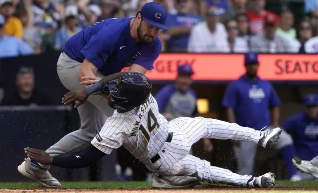 Milwaukee Brewers' Andruw Monasterio (14) is tagged out at home by Chicago Cubs' Luke Little, top, after being caught in a rundown during the seventh inning of a baseball game Saturday, June 29, 2024, in Milwaukee. (AP Photo/Aaron Gash)