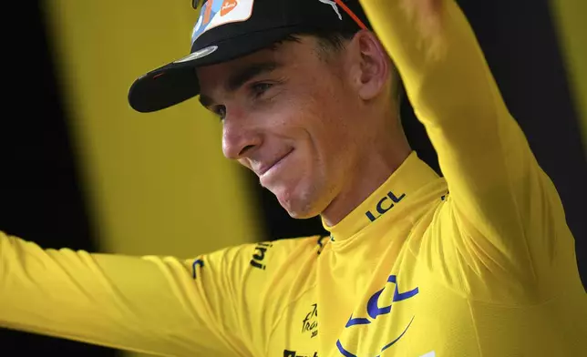 New overall leader France's Romain Bardet, wearing the overall leader's yellow jersey, celebrates on the podium after the first stage of the Tour de France cycling race over 206 kilometers (128 miles) with start in Florence and finish in Rimini, Italy, Saturday, June 29, 2024. (AP Photo/Daniel Cole)