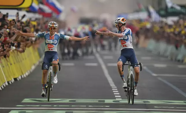 New overall leader France's Romain Bardet, right, thanked teammate Netherlands' Frank van den Broek as he crosses the finish line to win the first stage of the Tour de France cycling race over 206 kilometers (128 miles) with start in Florence and finish in Rimini, Italy, Saturday, June 29, 2024. (AP Photo/Daniel Cole)