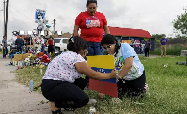 FILE - Patty Limon watches her daughters Annaalexis Limon and Monica Limon place a Venezuelan flag, painted by Annaalexis, at a memorial where eight migrants were killed, and several others injured the day before while waiting at a bus stop in Brownsville, Texas, Monday, May 8, 2023. A Texas jury has found George Alvarez guilty of intoxication manslaughter, Friday, June 28, 2024 over the deaths of eight people who were struck by an SUV that plowed into a crowded bus stop outside a migrant shelter on the U.S.-Mexico border. (AP Photo/Michael Gonzalez, File)