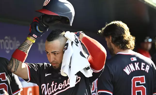 Washington Nationals Eddie Rosario, left, wipes the perspiration off his head in the dugout during the eighth inning of a baseball game against the Arizona Diamondbacks Wednesday, June 19, 2024, in Washington. (AP Photo/John McDonnell)