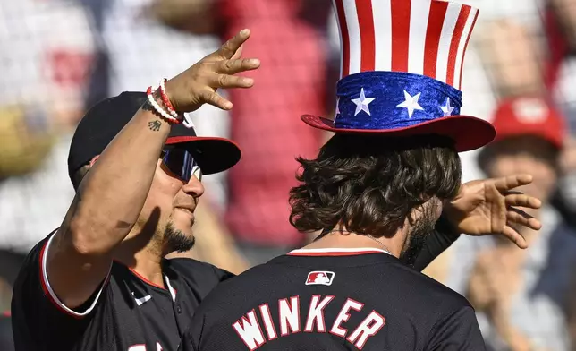 Washington Nationals' Ildemaro Vargas, left, crowns Nationals' Jesse Winker with the home run top hat after Winker hit a go-ahead two-run home run during the sixth inning of a baseball game against the Arizona Diamondbacks Wednesday, June 19, 2024, in Washington. (AP Photo/John McDonnell)