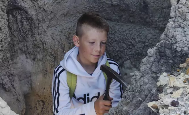 In this photo provided by Giant Screen Films, Jessin Fisher digs for fossils on public lands near his home in Marmath, N.D. (Sam Fisher/Giant Screen Films via AP)