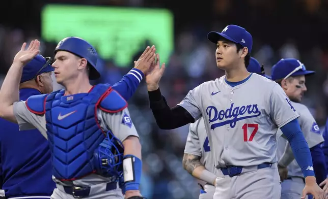 Los Angeles Dodgers' Shohei Ohtani, right, celebrates with manager Dave Roberts, back left, after the team's victory over the San Francisco Giants in a baseball game Saturday, June 29, 2024, in San Francisco. (AP Photo/Godofredo A. Vásquez)