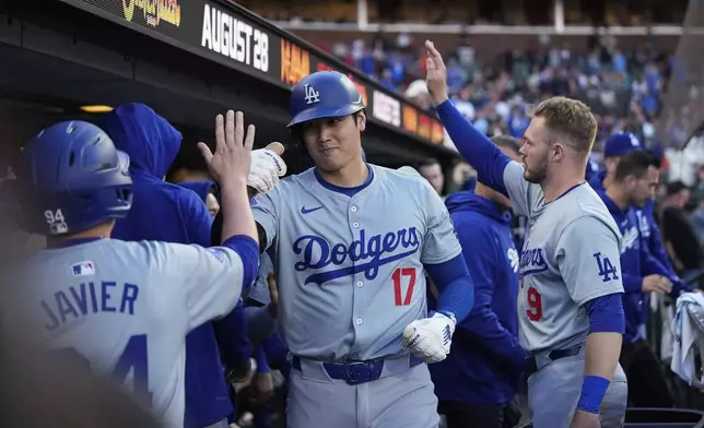 Los Angeles Dodgers' Shohei Ohtani, center, celebrates with teammates in the dugout after scoring against the San Francisco Giants on Will Smith's double during the 11th inning of a baseball game Saturday, June 29, 2024, in San Francisco. (AP Photo/Godofredo A. Vásquez)