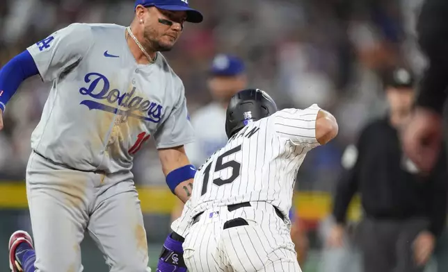 Los Angeles Dodgers shortstop Miguel Rojas, left, tags out Colorado Rockies' Hunter Goodman in a rundown between first and second base in the seventh inning of a baseball game Tuesday, June 18, 2024, in Denver. (AP Photo/David Zalubowski)
