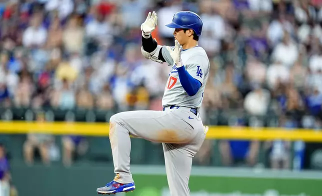 Los Angeles Dodgers' Shohei Ohtani gestures to the dugout after reaching second base by hitting a double off Colorado Rockies relief pitcher Jake Bird in the sixth inning of a baseball game Monday, June 17, 2024, in Denver. (AP Photo/David Zalubowski)