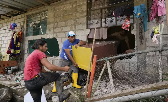 People rescue belongings from their house damaged by a landslide set by heavy rains in El Placer, Ecuador, Monday, June 17, 2024. (AP Photo/Dolores Ochoa)