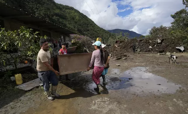 People rescue their belongings from their house destroyed by a landslide in El Placer, Ecuador, Monday, June 17, 2024. (AP Photo/Dolores Ochoa)