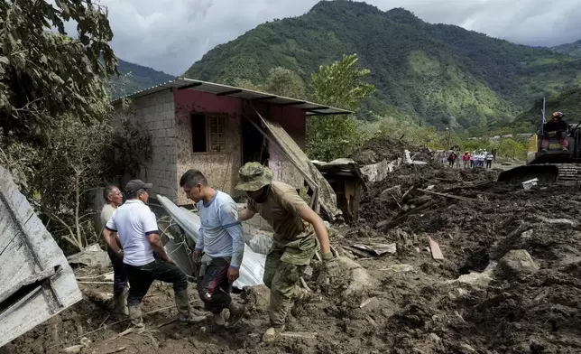A resident, second from right, reacts after landslides damaged his house in El Placer, Ecuador, Monday, June 17, 2024. (AP Photo/Dolores Ochoa)