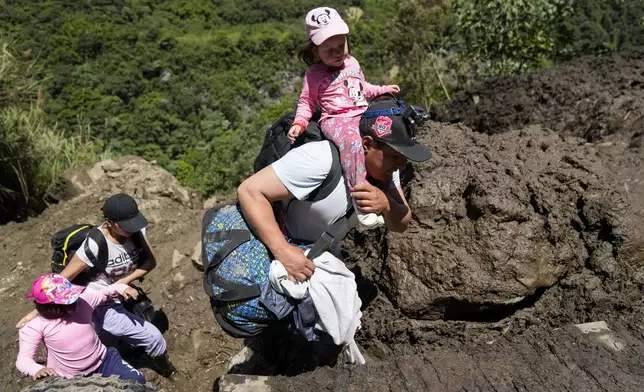 Residents traverse terrain that experienced landslides in Banos, Ecuador, Monday, June 17, 2024. (AP Photo/Dolores Ochoa)